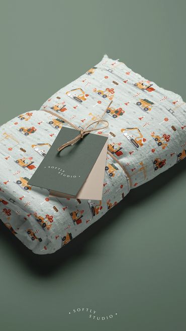 Soft muslin fabric with construction-themed Christmas trucks and tools, neatly tied with tags.