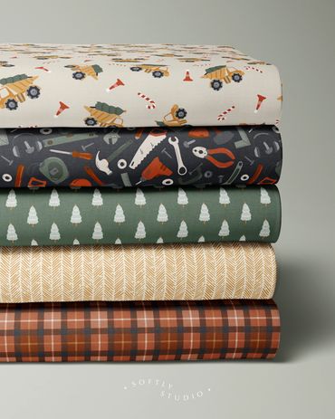 A festive stack of Christmas fabrics featuring trucks, tools, trees, herringbone, and plaid designs.