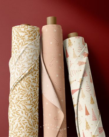 Three fabric rolls featuring leaves, candy canes, and festive Christmas trees in soft holiday tones.