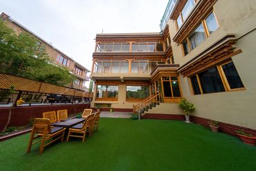 Outdoor patio area with wooden furniture and green artificial grass.