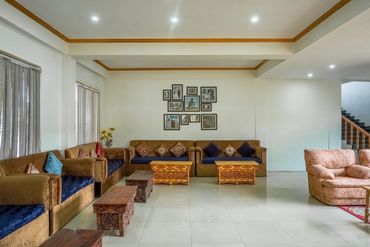 Spacious living room with brown sofas, wooden tables, and framed wall art.