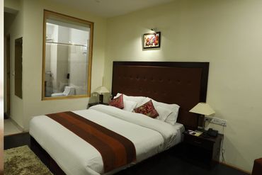 Cozy hotel room with a large bed and visible bathroom through glass.