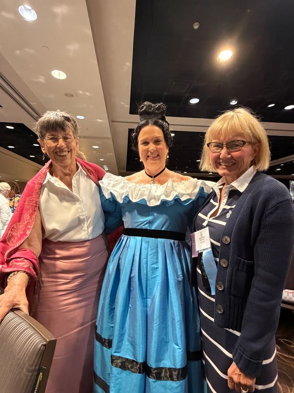 Three women smiling at an indoor event.