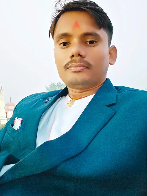 Man with a red tilak on forehead wearing a blue blazer and white shirt.