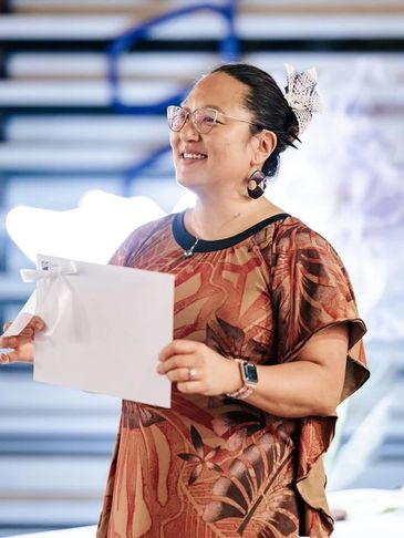 Woman smiling while holding papers and speaking.