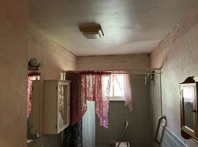 Dimly lit bathroom with pink curtains and a vintage aesthetic.
