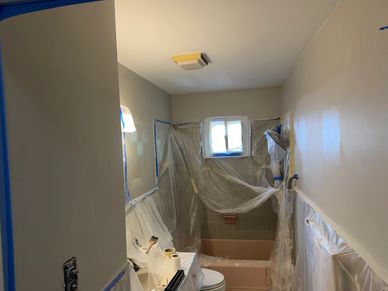 Bathroom under renovation with plastic coverings and taped edges.