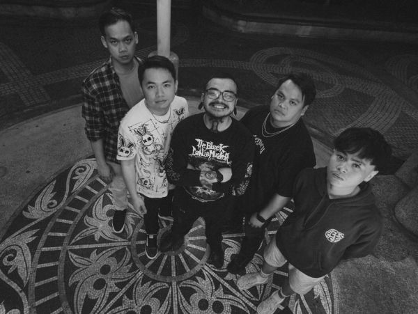 Five young men posing on a decorative circular floor, looking up at the camera.