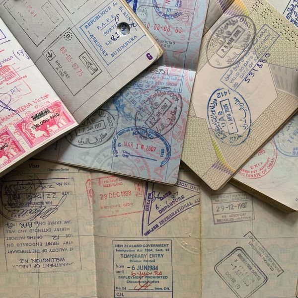 Collection of open passport pages showing travel stamps from various countries.