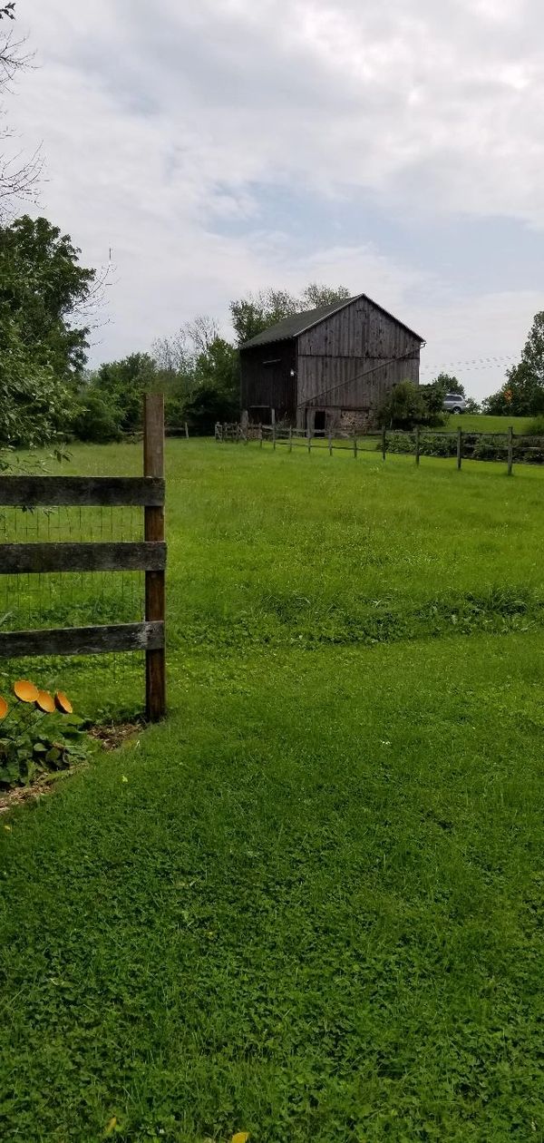 Rustic barn in a green field under a cloudy sky.