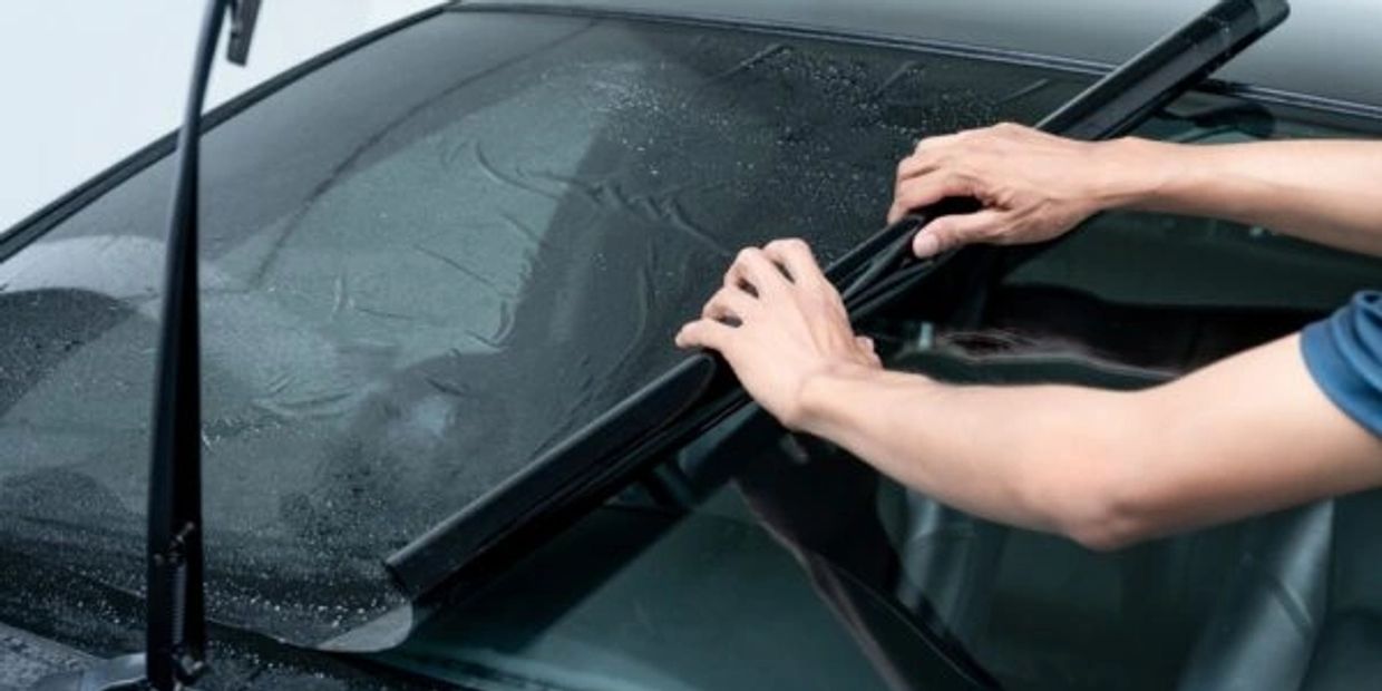 Person replacing a car windshield wiper blade.