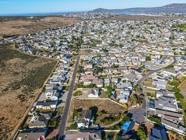Aerial view of a suburban neighborhood with houses and roads near a coastline.