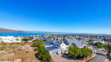 Coastal town with white houses under a clear blue sky by the sea.