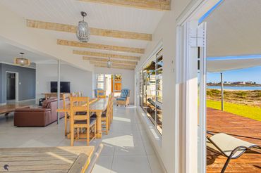 Bright, spacious dining and living area with ocean view and wooden furniture.