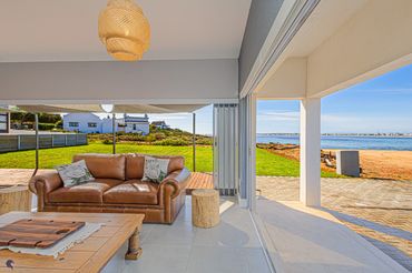 Cozy living room with leather sofa and ocean view through large sliding doors.