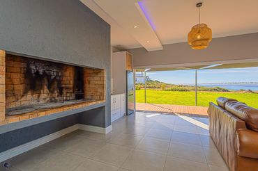 Modern living room with fireplace, leather sofa, and ocean view.
