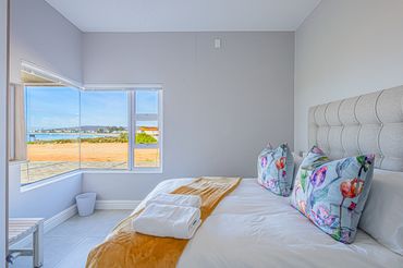 Bright bedroom with floral pillows and a view of the outdoors.
