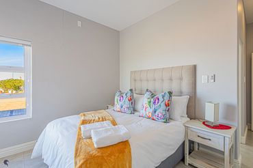 Bright bedroom with a cozy bed, floral pillows, and a yellow throw blanket.