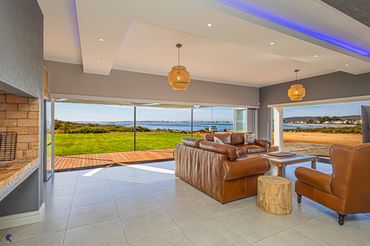 Spacious living room with leather sofas and panoramic water views.