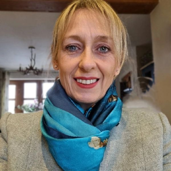 Woman smiling indoors with a patterned blue scarf.