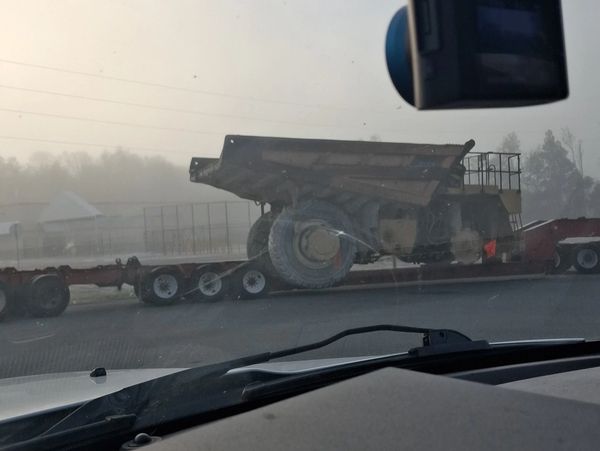 Large dump truck being transported on a flatbed trailer.