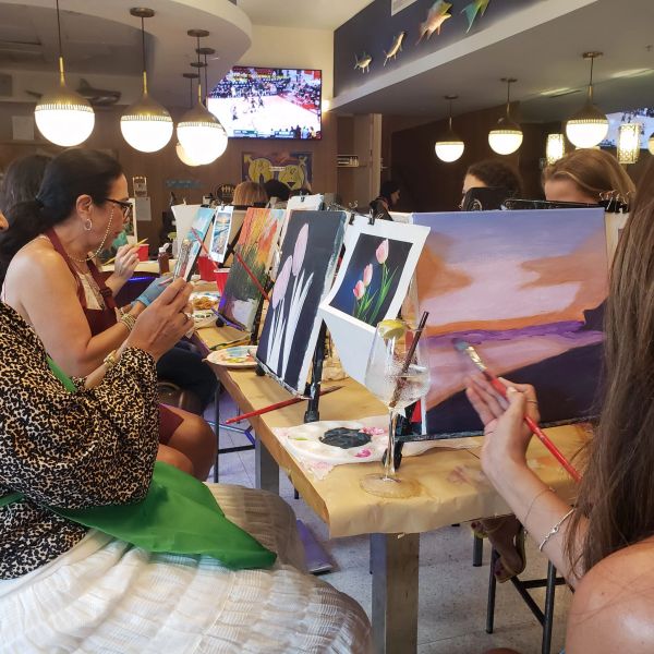 Group painting session with people focused on their canvases.