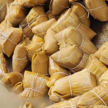 Traditional tamales wrapped in corn husks soaking in water.