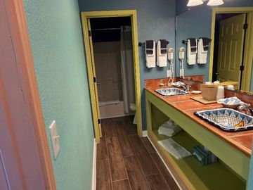 Bathroom with wooden floor and green accents, featuring a sink and towels.