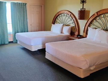 Two neatly made beds with decorative headboards in a hotel room.