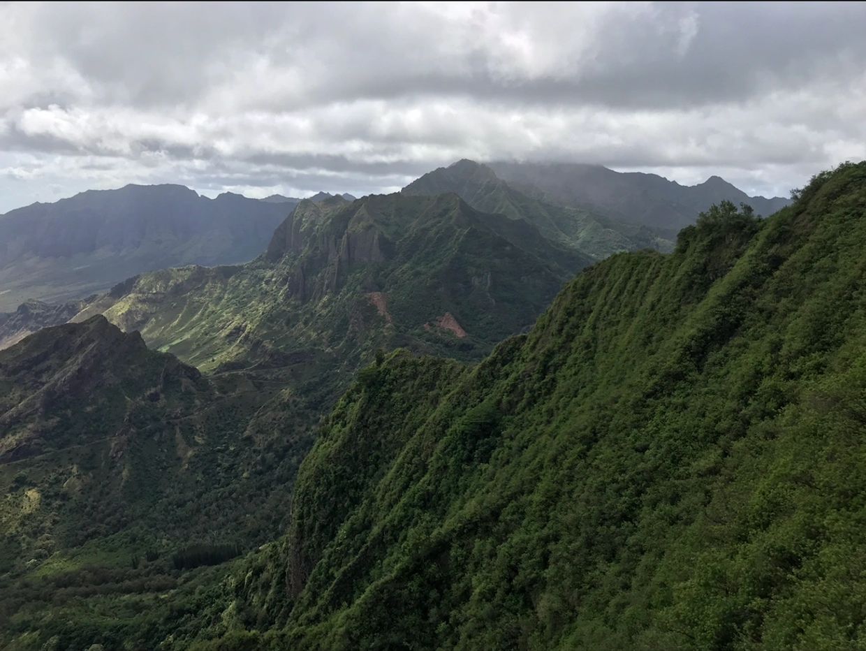 Lush green mountains under cloudy skies.