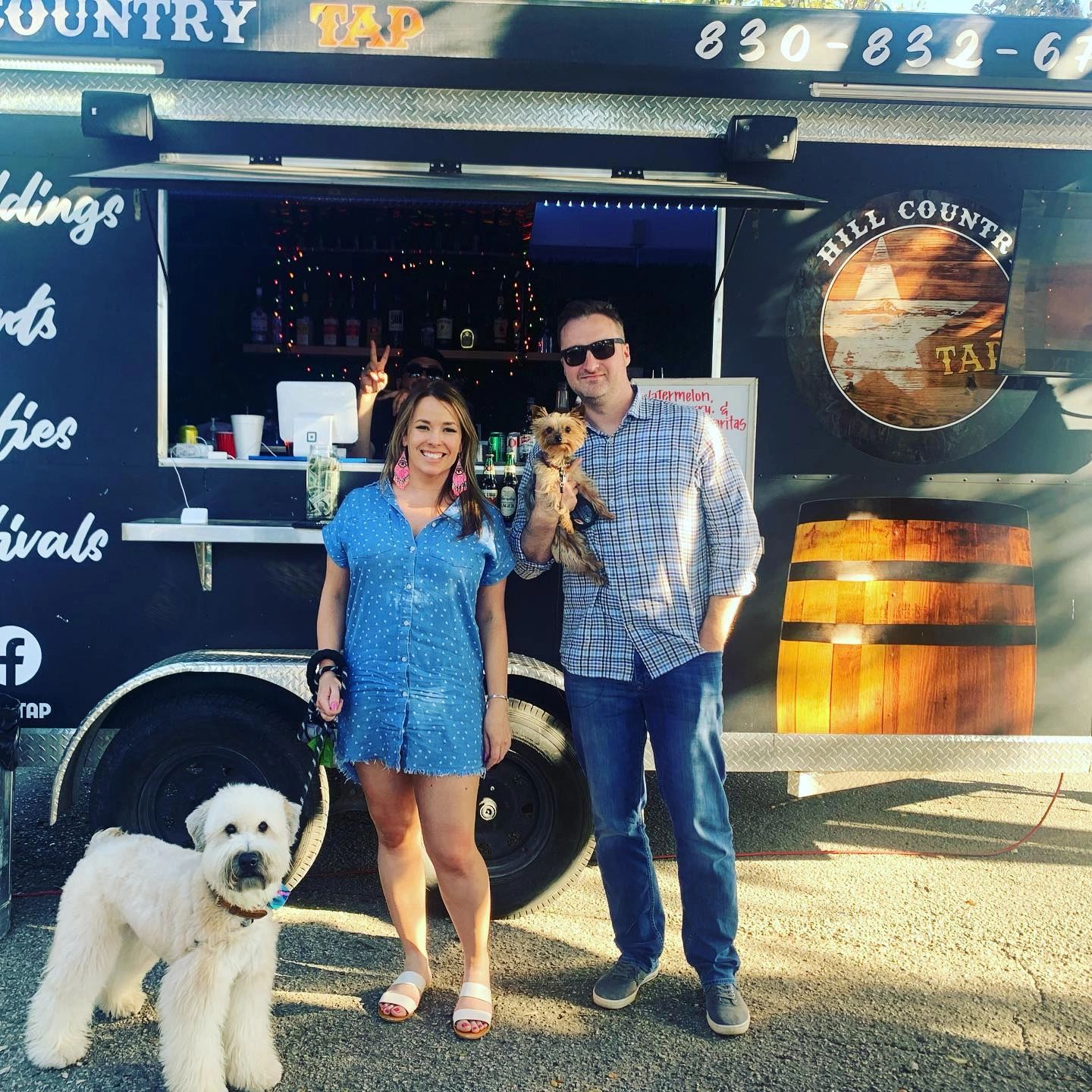 Couple with two dogs in front of mobile rolling bar waiting to order drinks