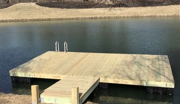 A wooden dock extending into a calm pond with a metal ladder.