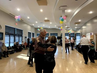 Elderly couples dancing in a decorated community hall.
