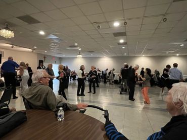 Elderly people dancing and socializing in a community hall.