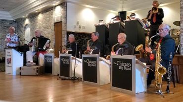 The Chicago Big Band performing indoors with various musicians playing instruments.