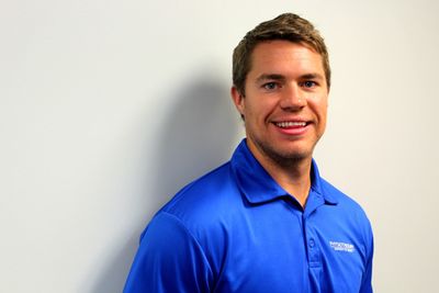 Smiling man in a blue polo shirt against a white background.