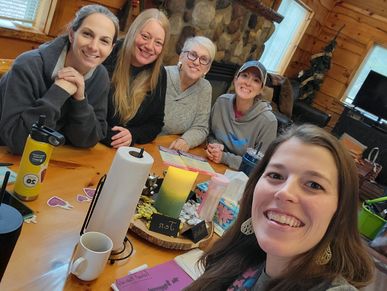 selfie of group of women sitting at a table in a cabin