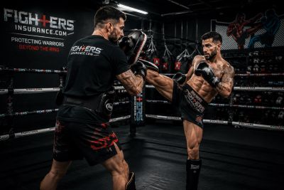 A coach and student practicing kickboxing in a ring.