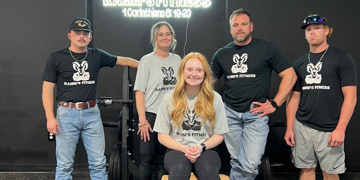 Group of five people in gym shirts posing together.