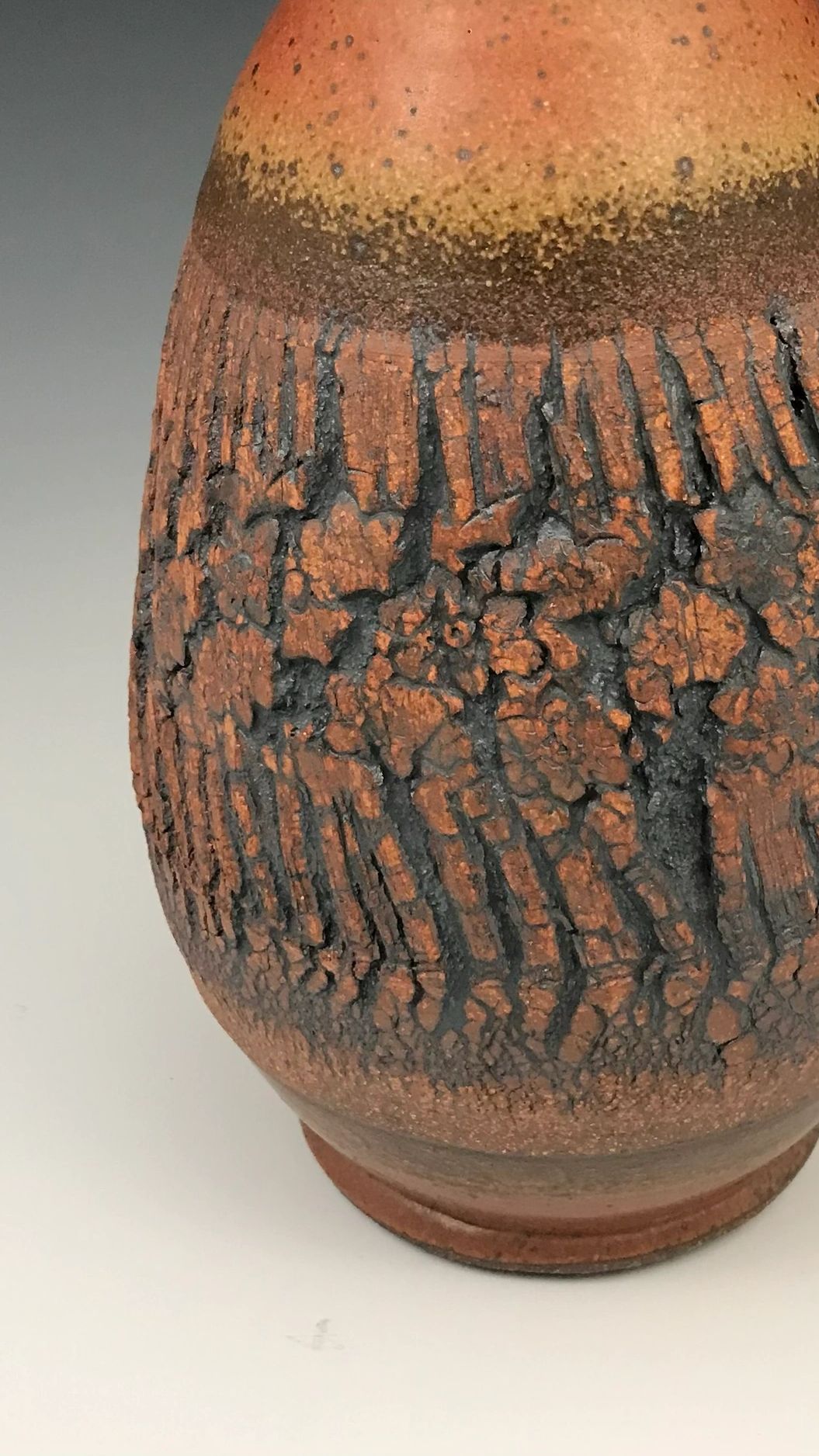 Textured ceramic vase with earthy tones and a rough, cracked surface pattern.