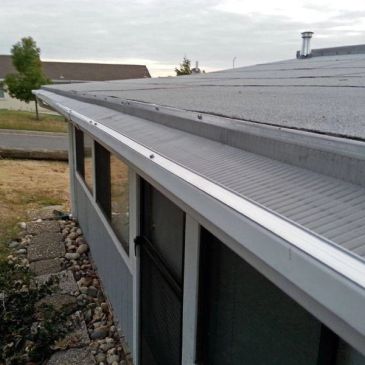 A close-up view of a clean, newly installed gutter on a house roof.