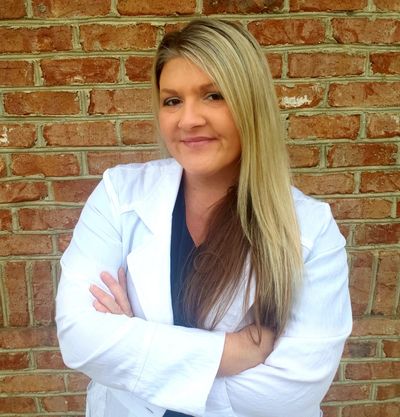 Laura Hill, FNP-C standing with arms crossed and smiling