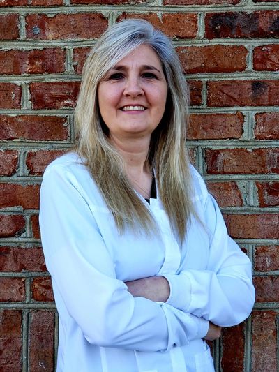 Angela Hill, RN standing with arms crossed smiling