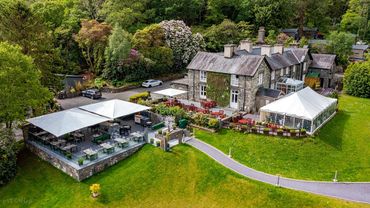 Charming Aberdunant Hall Hotel with outdoor seating and lush greenery.
