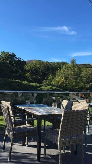 Outdoor patio with wicker chairs and tables under a clear blue sky.
