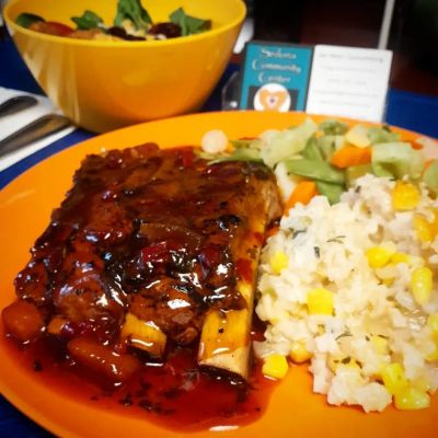 Barbecue ribs with rice and mixed vegetables on a plate.