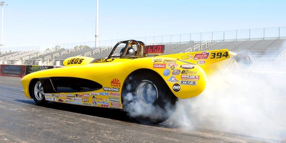 Yellow drag racing car performing a burnout on the track.