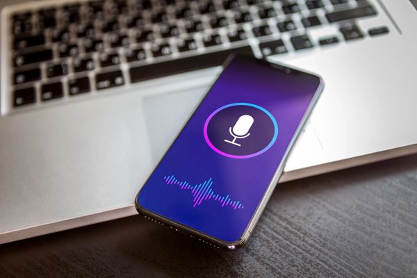 Smartphone with a microphone icon and sound waves on the screen.