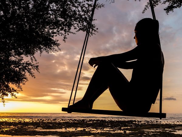Silhouette of woman on swing