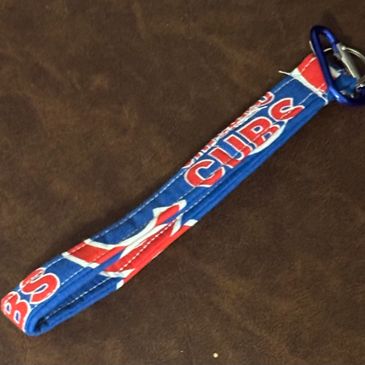 Blue Cubs wristband with carabiner on brown surface.